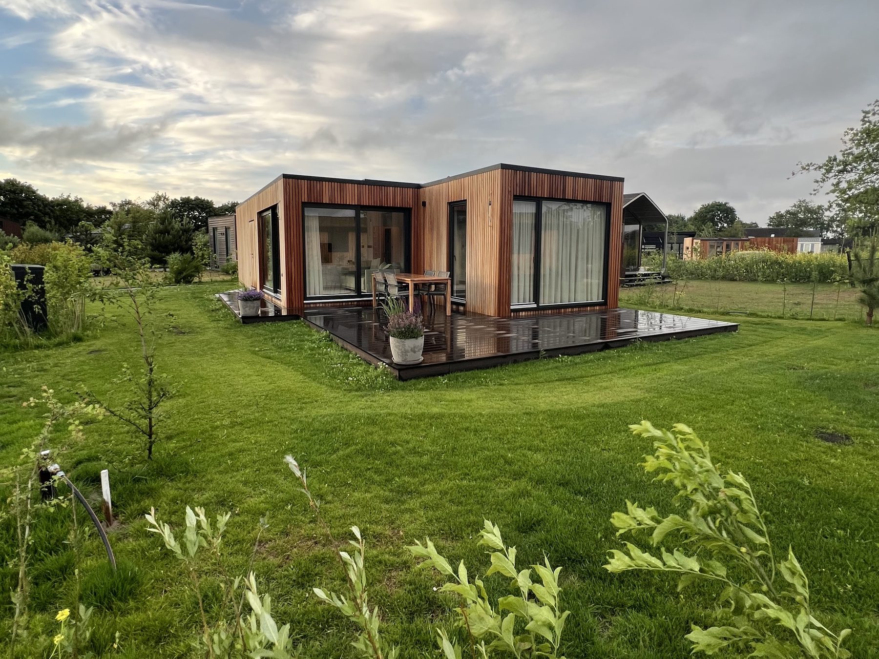 Tiny House mit Holzfassade und Terrasse auf einer Wiese in den Niederlanden im Abendlicht